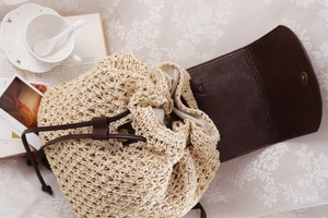Detail of hand-woven straw bag with dark brown leather flap and drawstring closure