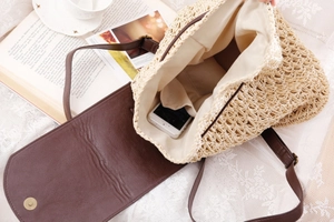Detail of straw woven shoulder bag interior with fabric lining and magnetic metal snap closure