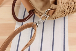 Detail of hand-woven straw bag featuring resin handles and silver metal hardware