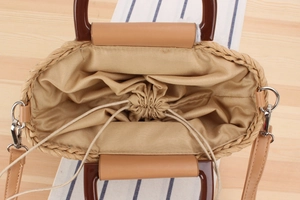 Close-up of woven straw bag interior with drawstring lining and resin handle