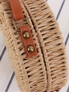 Natural round woven straw crossbody bag with brown leather strap and floral lining details