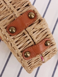 Minimalist round woven crossbody bag with brown leather straps and vintage bronze rivets