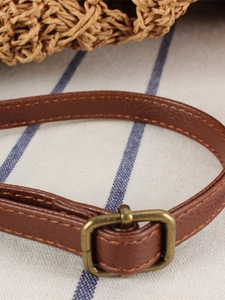 Brown lychee leather strap with bronze buckle on woven hollow bucket beach bag