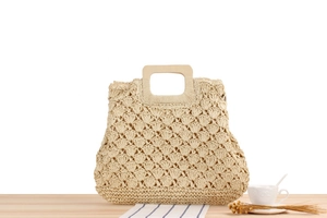 Détail du sac en paille beige au crochet avec texture coquille et anses en bois