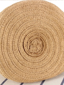 Handcrafted round straw woven bucket bag with detailed spiral texture on striped fabric