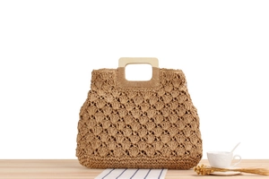 Détail du sac de plage tissé à la main en corde de papier avec anse en bois sur une table
