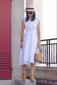 Detail of a handmade woven tote bag styled with a white sleeveless vacation dress