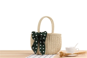 Detailed macro of a beige straw handbag with a green polka dot silk scarf handle decor
