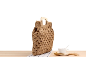 Détail d'un sac cabas tissé main avec motifs à fleurs ajourés et poignées en bois