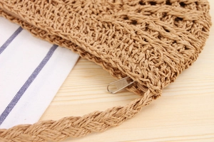 Macro detail of hand-woven straw bag with a silver metal zipper and hollow texture