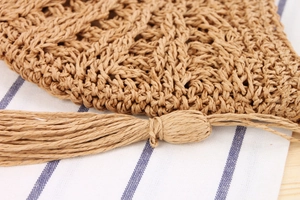 Detailed macro view of hollow-out woven texture and long tassel on a straw beach bag