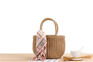 Detail of hand-woven straw tote bag with elegant pink printed scarf handle decoration