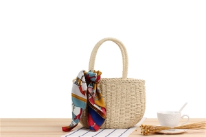 Detail of handmade cream woven tote bag with vintage print silk scarf on a wooden table