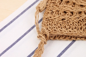 Detail shot of a handmade woven straw bag featuring a secure zipper and braided strap