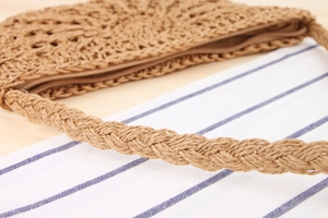 Detail of hand-woven straw crossbody bag with braided shoulder strap and zipper closure