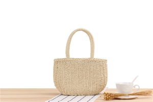Detail of hand-woven straw tote bag with textured beige patterns on a wooden surface
