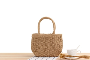 Close-up of hand-woven straw tote bag with natural fiber texture on a wooden desk