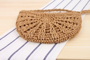 Detailed close-up of semi-circular woven straw bag with hollow texture for beach vacation