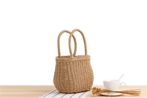 Detailed view of handmade woven straw tote bag with textured patterns on wooden surface