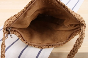 Interior view of handwoven straw crossbody bag with fabric lining and metal zipper