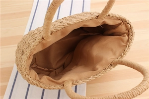 Detailed top view of a handmade straw tote bag showing interior lining and round handle