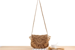 Detail of a handmade straw shoulder bag with long fringes and woven strap for summer