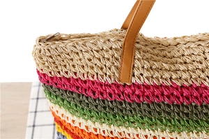 Détail du sac tressé arc-en-ciel montrant la fermeture éclair et la poignée en cuir brun