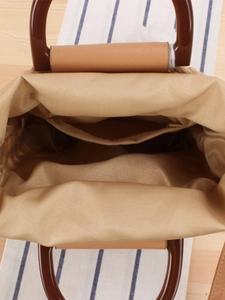 Top view of woven straw tote bag with brown handles and khaki lining interior