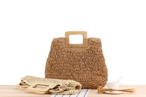 Détail de sacs en paille tissés main avec poignées rectangulaires en bois sur table