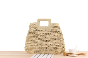 Détail du sac tissé beige avec maille évidée et poignée carrée en bois naturel
