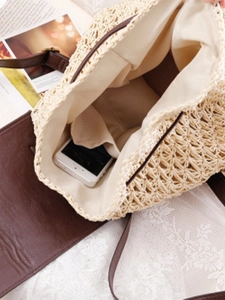 Beige paper rope woven beach bag with brown leather flap showing interior phone storage