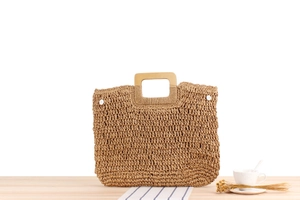 Détail d'un sac en paille tissé avec texture naturelle et poignée carrée en bois