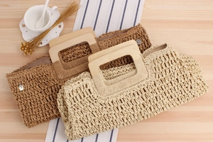 Détail de sacs à main tressés avec poignées en bois sur une table en bois clair