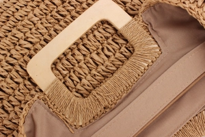 Gros plan du sac en paille tissée avec poignée carrée en bois et doublure beige