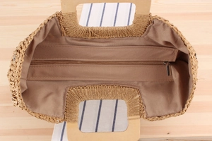 Vue de dessus d'un sac en paille avec doublure foncée, fermeture éclair et anse en bois