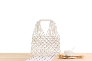 Detailed macro view of white handmade cotton rope mesh bag with thick braided handles