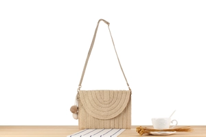 Détail du sac à bandoulière en paille tressée beige avec pompons décoratifs