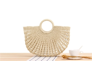 Detailed view of handmade paper rope woven beach bag with hollow mesh on wooden surface