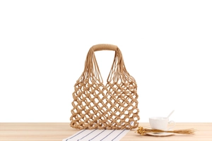 Close-up of handmade hollow woven tote bag with reinforced handle on wooden table