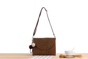 Détail de la texture d'un sac tressé en papier marron foncé avec pompons décoratifs