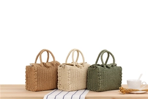 Close-up of woven crossbody bags in brown, beige, and green on a wooden table