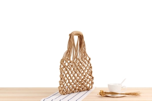 Detailed texture of handmade hollow woven cotton rope beach bag with diamond grid mesh