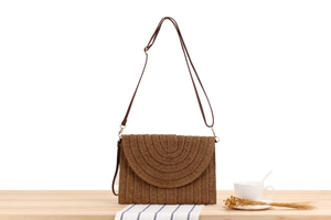 Détail de la texture tressée à la main et du rabat arrondi d'un sac de plage marron