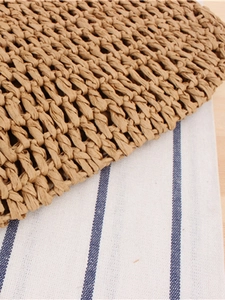 Handmade woven crochet tassel bag in brown straw texture on a striped background