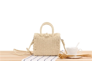 Detailed macro of the woven straw crossbody bag closure and top handle craftsmanship