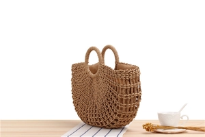 Detailed macro view of hollow mesh pattern and woven handles on a straw beach tote bag