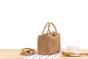Detailed view of handmade woven straw crossbody bag with circular handles and strap