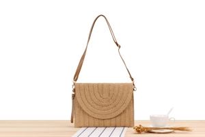 Détail du sac en paille tissé à la main avec texture circulaire et bandoulière en cuir
