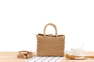 Detail shot of handwoven straw bag featuring natural textures and sturdy handles