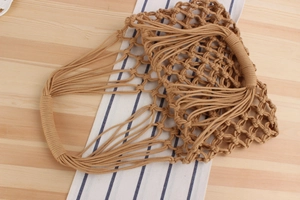 Macro detail of the khaki hand-woven cotton rope mesh bag with reinforced handles